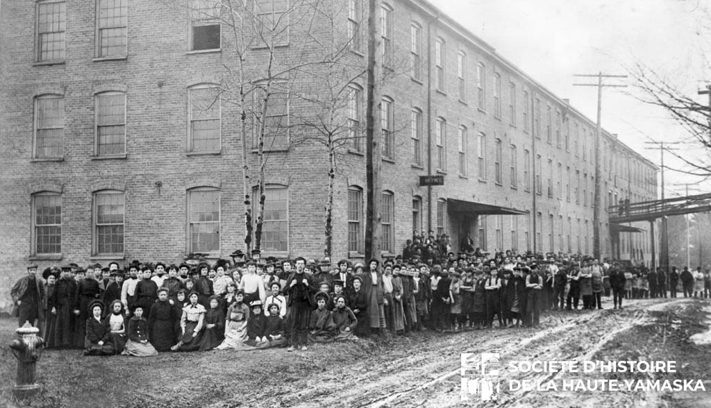 Les employé[e]s de l’Empire Tobacco, en 1909, devant la fabrique de la rue Cowie. (©Société d’histoire de la Haute-Yamaska, collection Photographies Granby et région, P70-S27-SS4-SSS21-D1-P1)